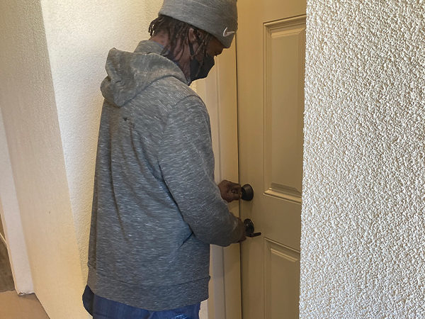 A man, wearing a gray hoodie and beanie, prepares to enter his new home, symbolizing hope and stability after homelessness.