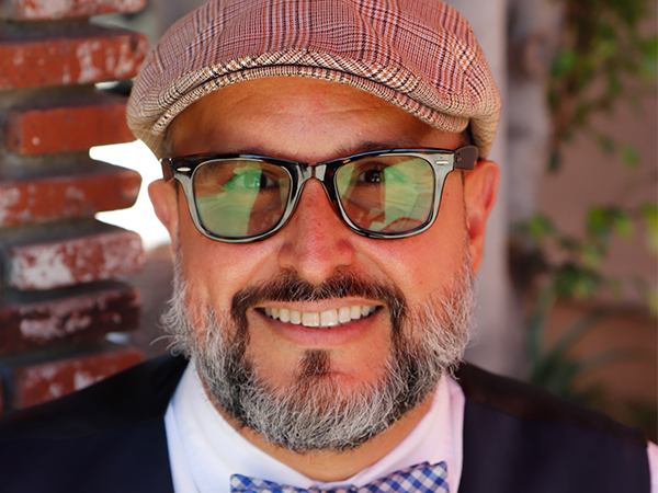 A smiling man in glasses and a cap shares his journey toward stability and hope in the Los Angeles community.
