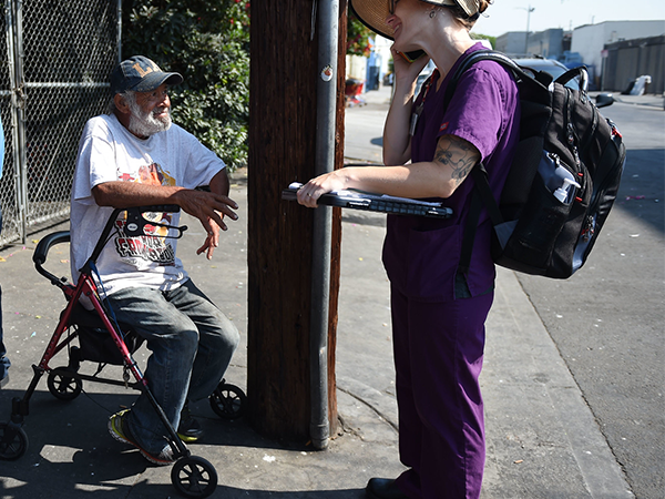 A outreach worker engages with an elderly man in need, fostering connection and support on a Los Angeles street.