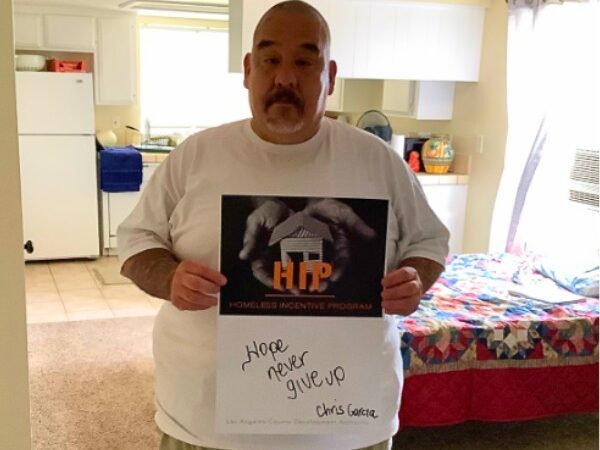 Christopher holds up a motivational sign in his new apartment.