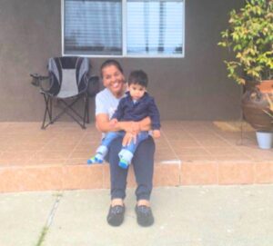 A recently housed family sits on the porch of their new home.