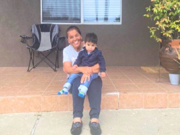 A recently housed family sits on the porch of their new home.