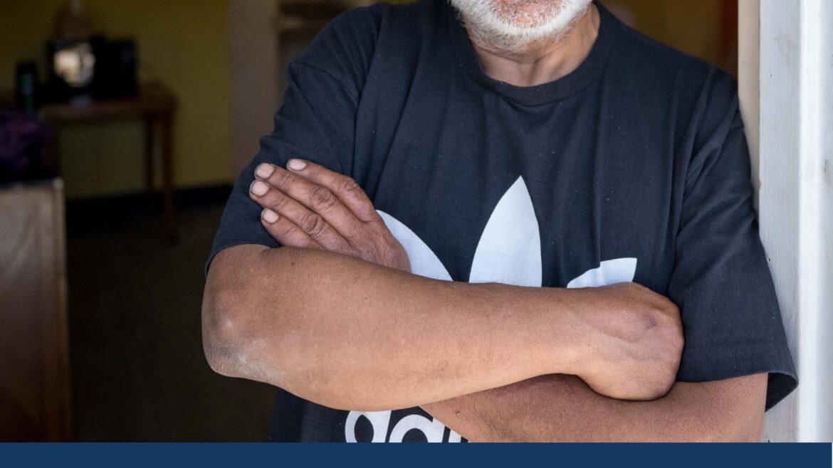 A smiling man stands confidently in a welcoming space, representing hope and support in the fight against homelessness.