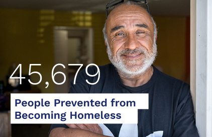 A smiling man stands in a doorway, representing the 45,679 individuals who received support to avoid homelessness.