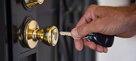 A hand holds a key poised to unlock a door, symbolizing new beginnings and access to stable housing.