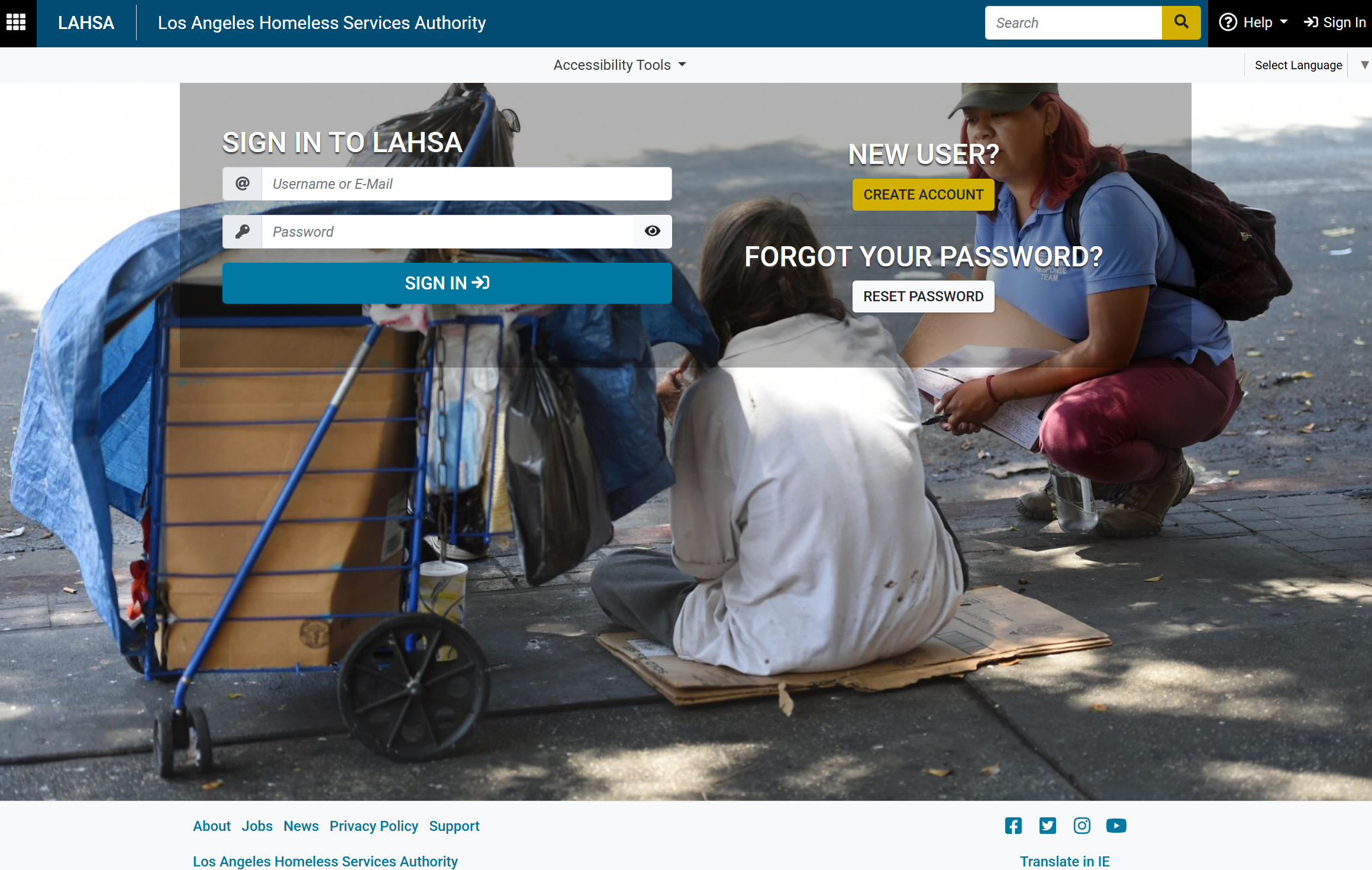A person sitting on the ground with a cart, receiving assistance from a compassionate outreach worker.
