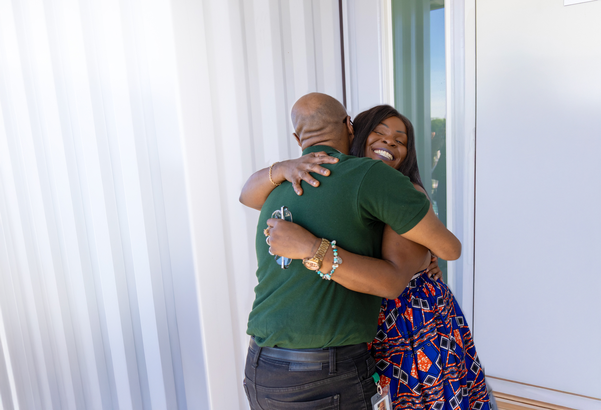A joyful reunion as two individuals embrace, celebrating a successful transition to stable housing and support services.