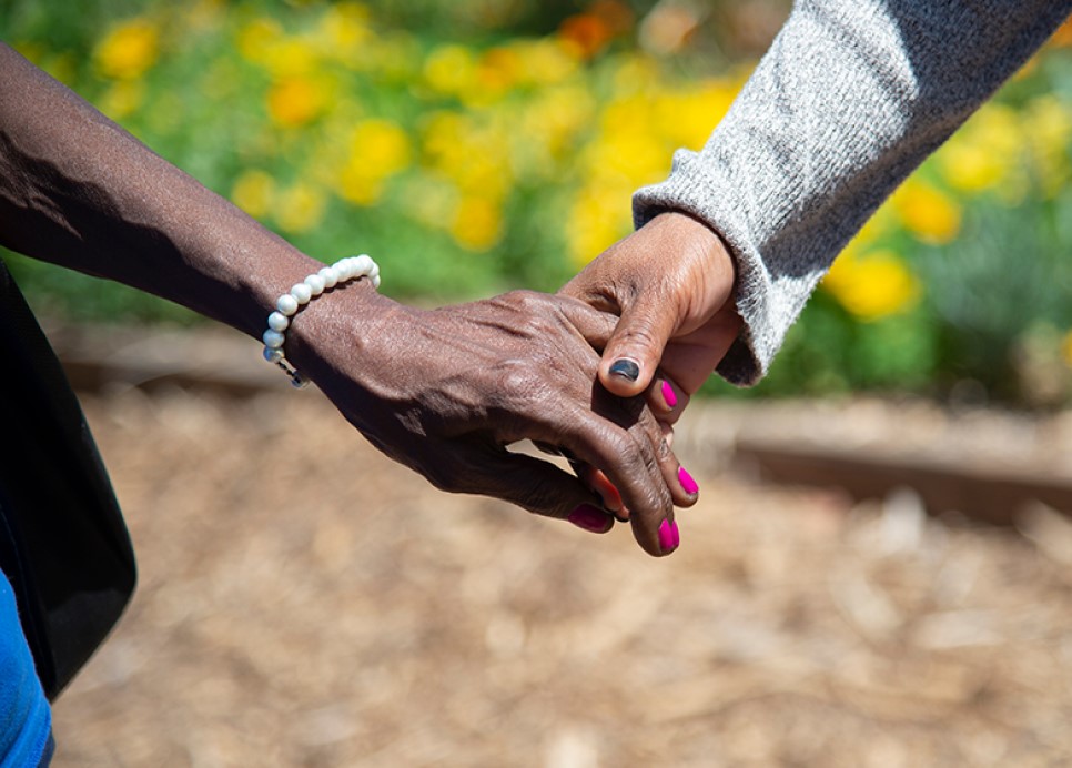 Two hands clasped together, symbolizing support and connection in the journey towards housing stability.