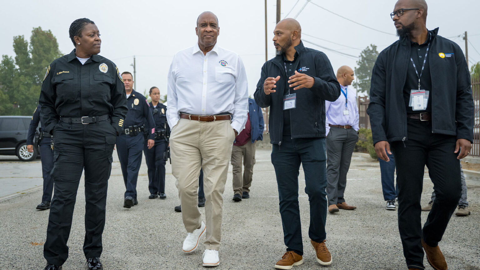 Community leaders walking together, discussing strategies to address homelessness and improve local support services.