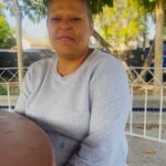 A woman wearing a grey sweatshirt smiles softly at the camera