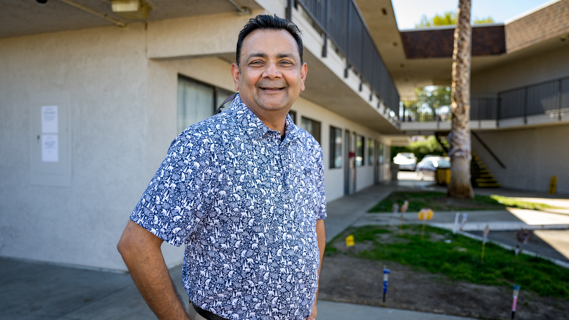 A smiling man stands outside a supportive housing facility, embodying hope and community resilience in the fight against homelessness.